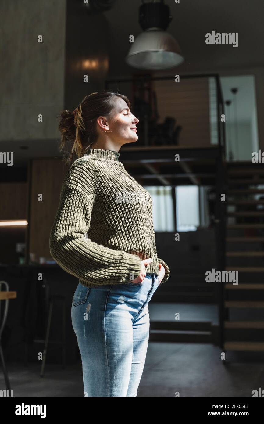 Sonnenlicht fällt auf Frau mit Händen in Taschen zu Hause stehen Stockfoto