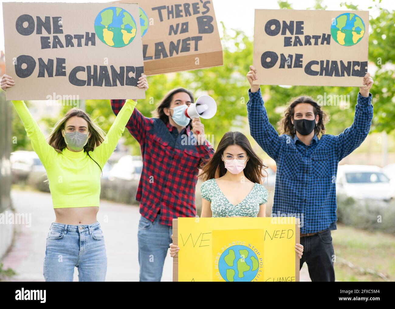 Männer mit Frauen, die während der Pandemie auf dem Weg zum Klimawandel ein Transparent halten Stockfoto