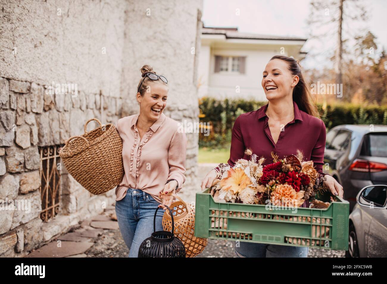 Frau mit Freund, der eine Blumenkaste trägt Stockfoto