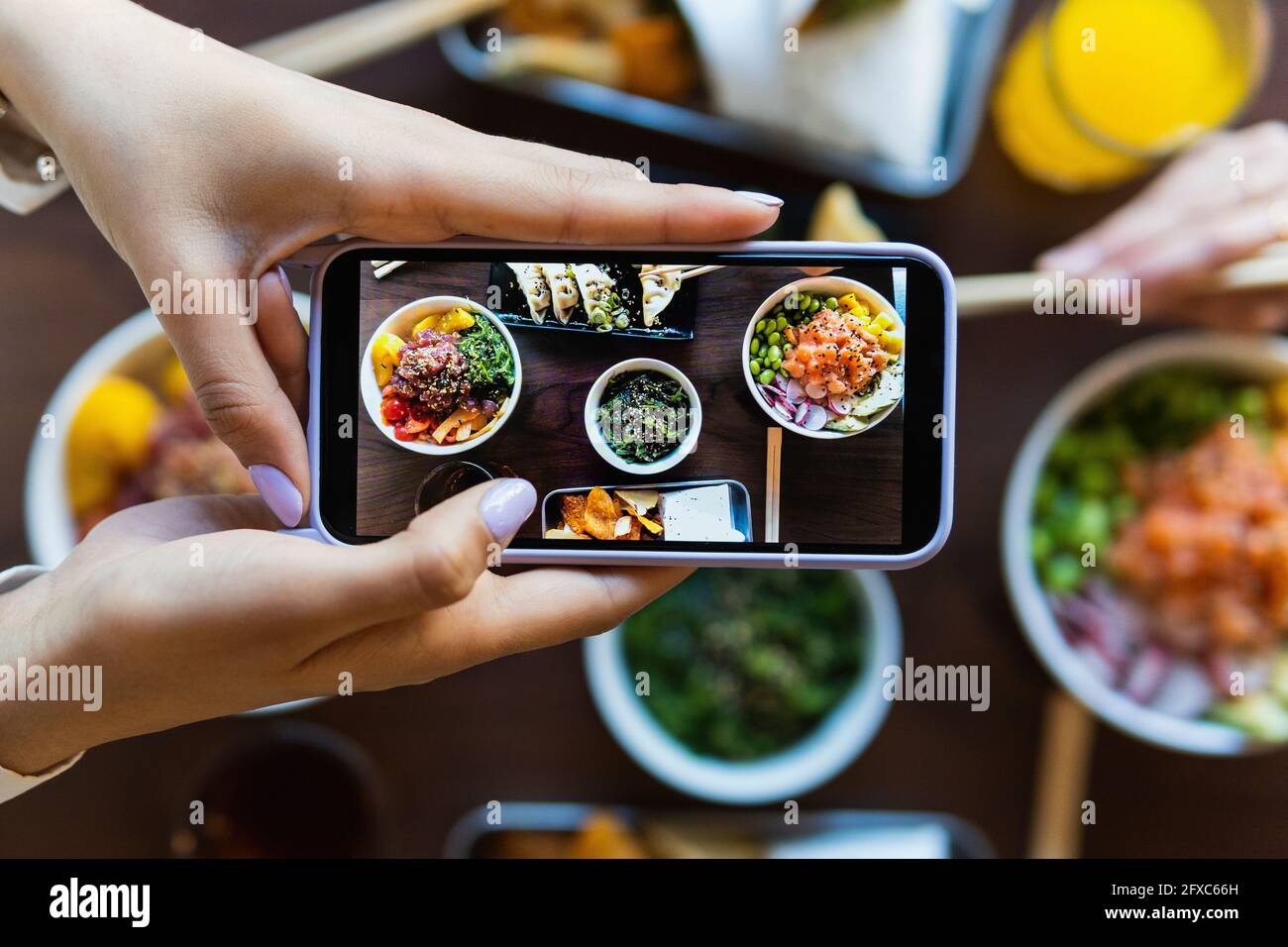 Junge Frau fotografiert Essen am Tisch im Restaurant Stockfoto