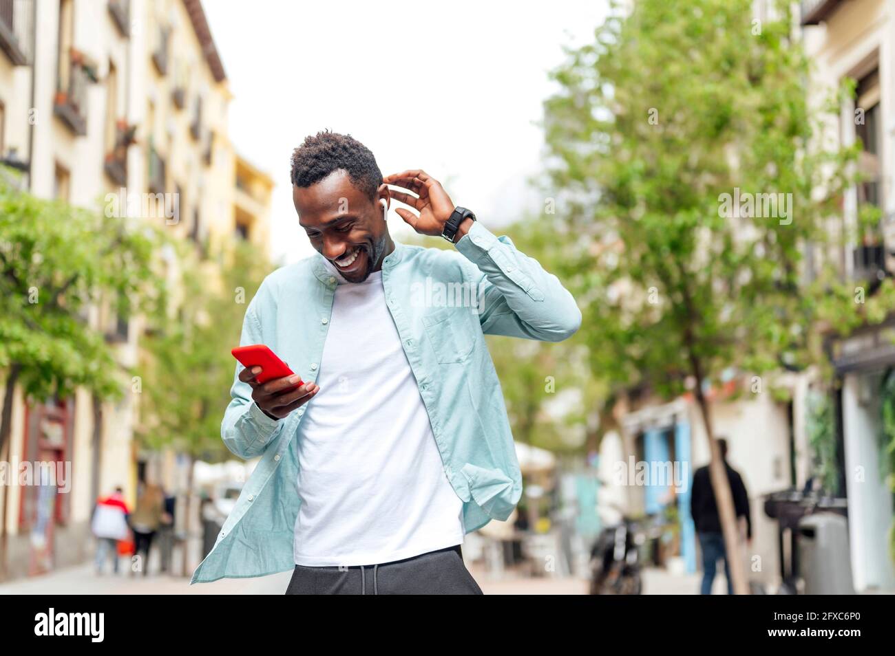 Junger Mann in legerer Kleidung mit Smartphone auf der Straße Stockfoto