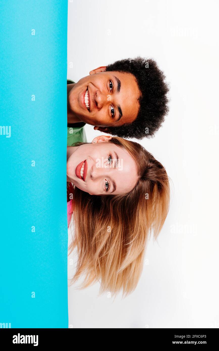Lächelnder junger Mann mit schöner Frau hinter blauem Hintergrund Stockfoto