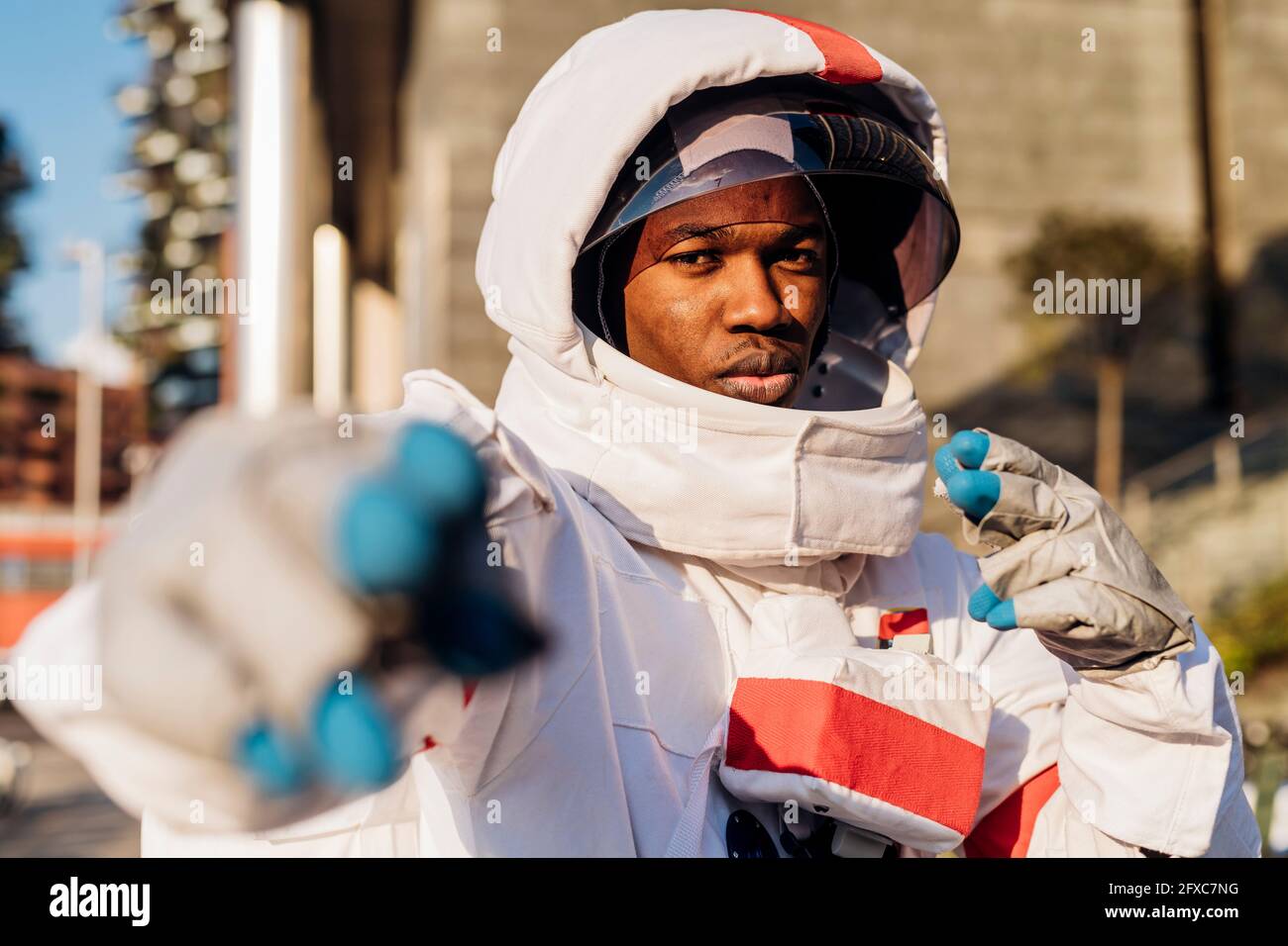 Männlicher Astronaut, der den Weltraumhelm gestikiert trägt Stockfoto