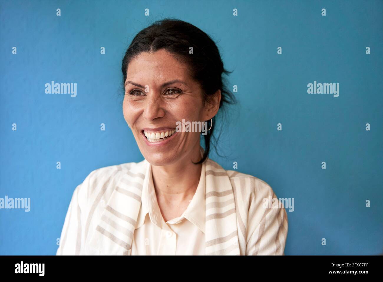 Lachende Frau mit braunen Augen vor der blauen Wand Stockfoto