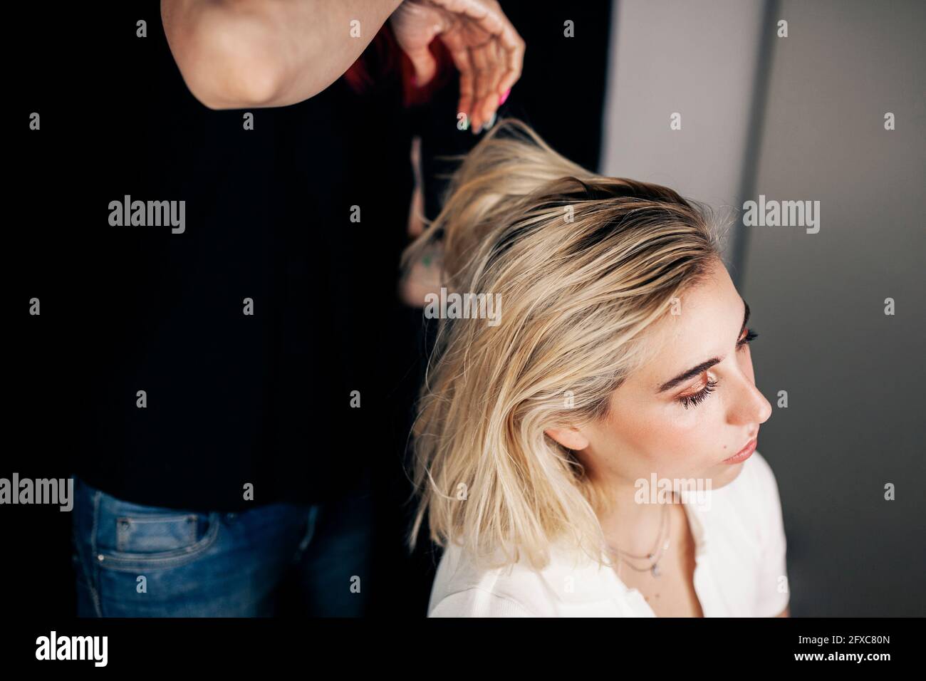 Weibliche Friseurin dabei Frisur von blonden Modell im Studio Stockfoto