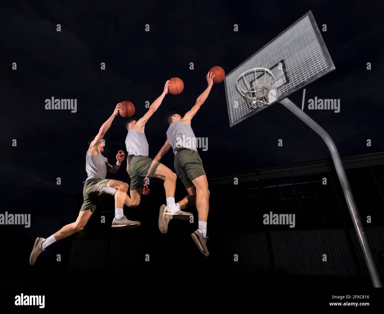 Multiple Bild von jungen Mann springen, während Basketball spielen in der Nacht Stockfoto
