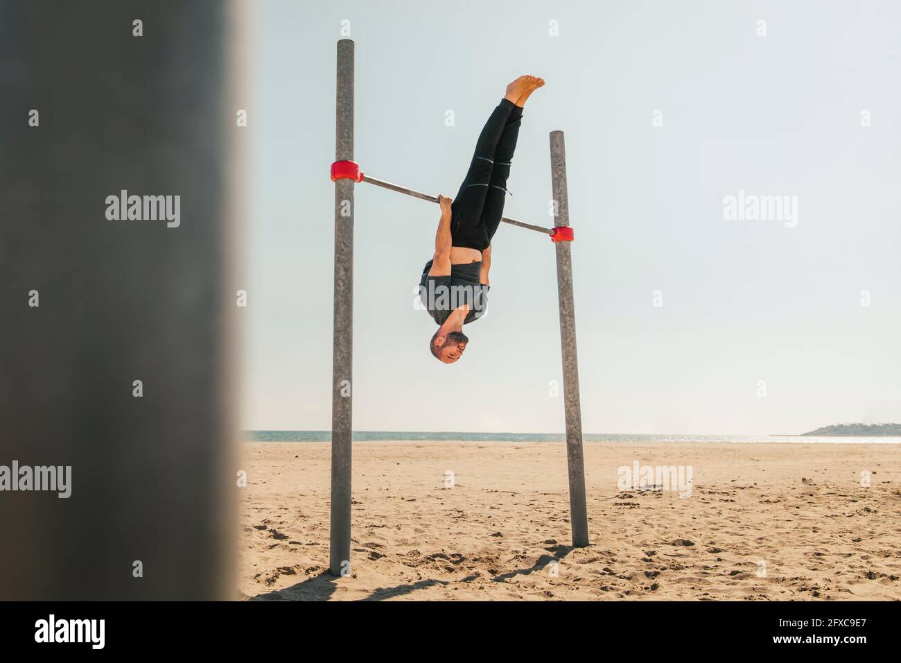 Männlicher Athlet, der an der Bar am Strand trainiert Stockfoto