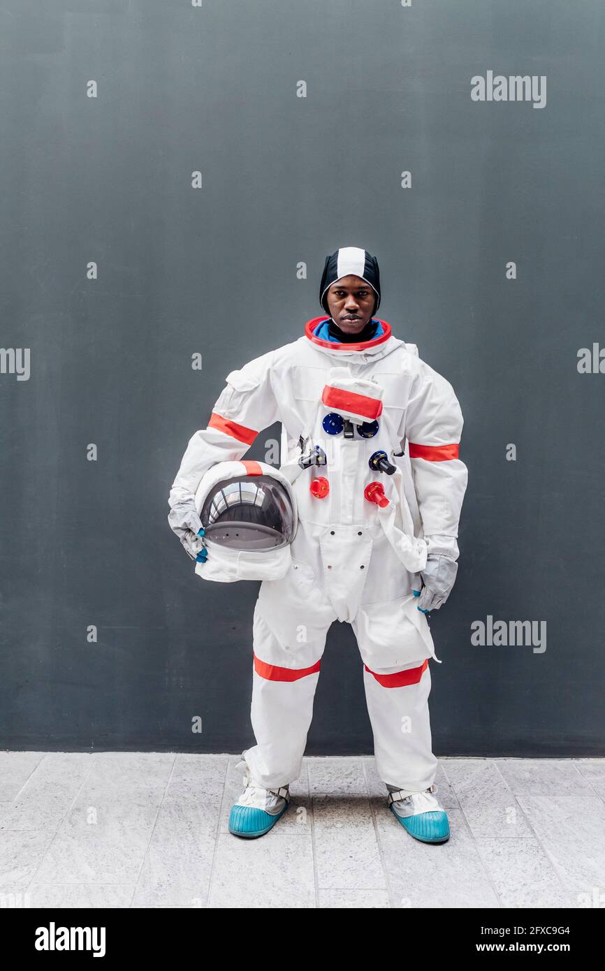 Männlicher Astronaut, der vor einer grauen Wand steht Stockfoto