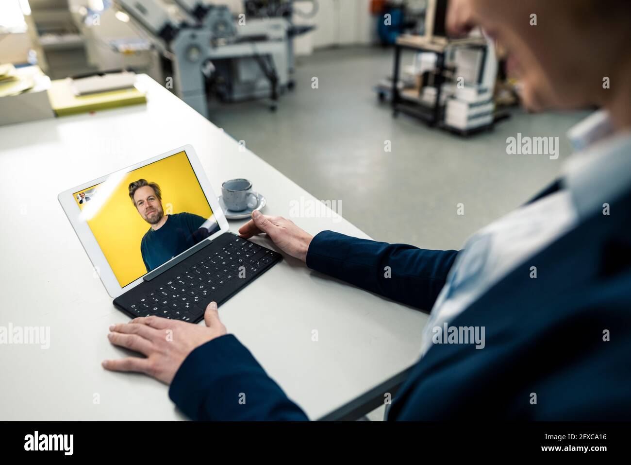 Geschäftsfrau im Gespräch mit einem Kollegen auf einem digitalen Tablet durch Videoanruf in der Industrie Stockfoto