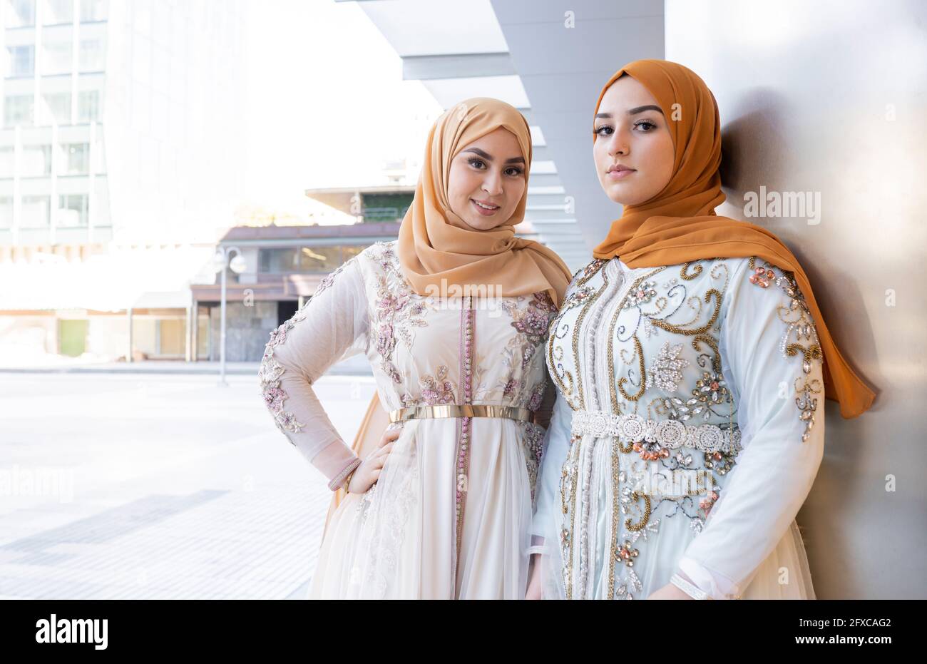 Schöne Freunde in Hijabs und Kleid stehen zusammen an der Wand Stockfoto