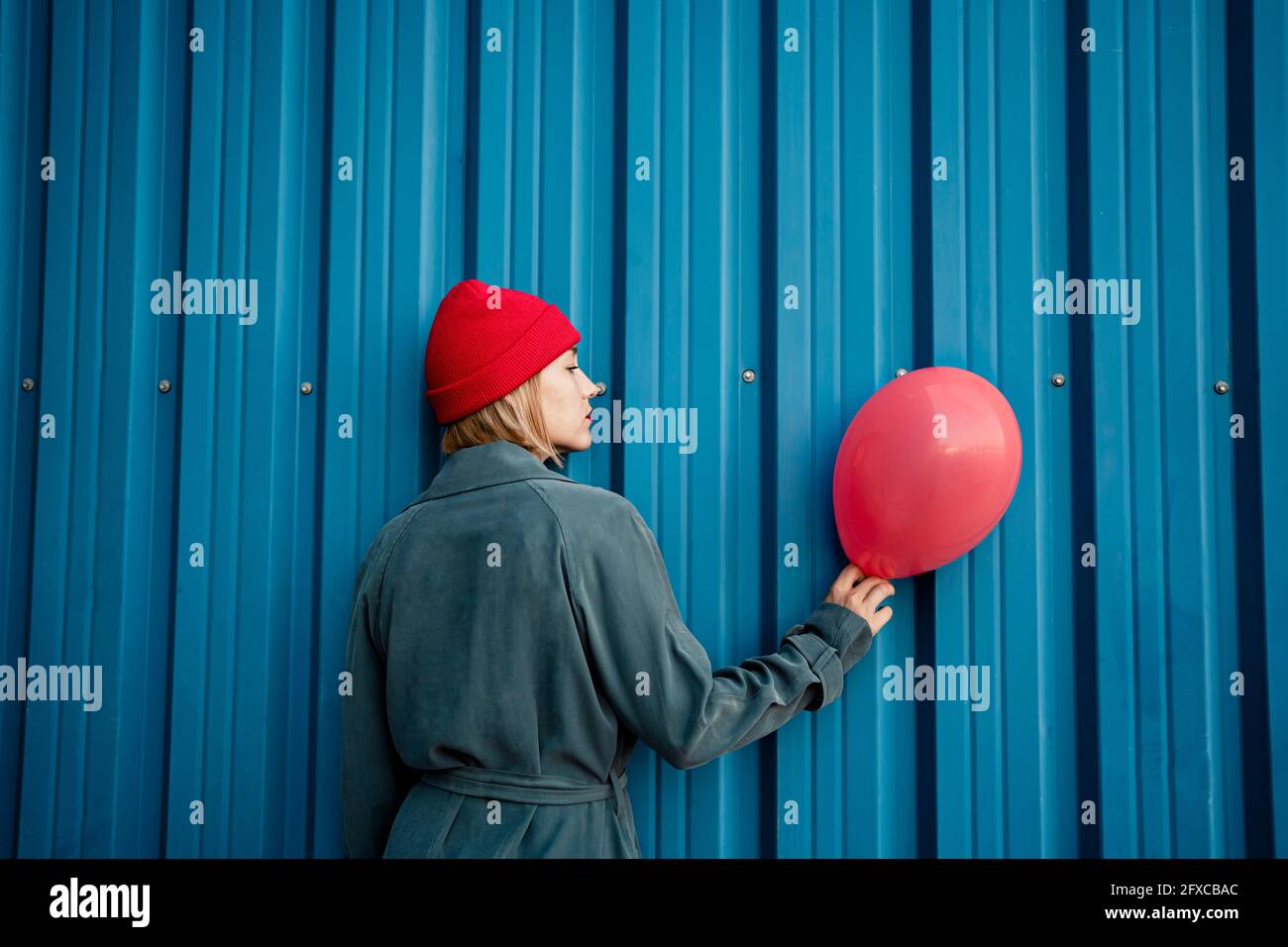 Frau mit mittlerem Erwachsenen, die den roten Ballon an einem blauen Verschluss hält Stockfoto