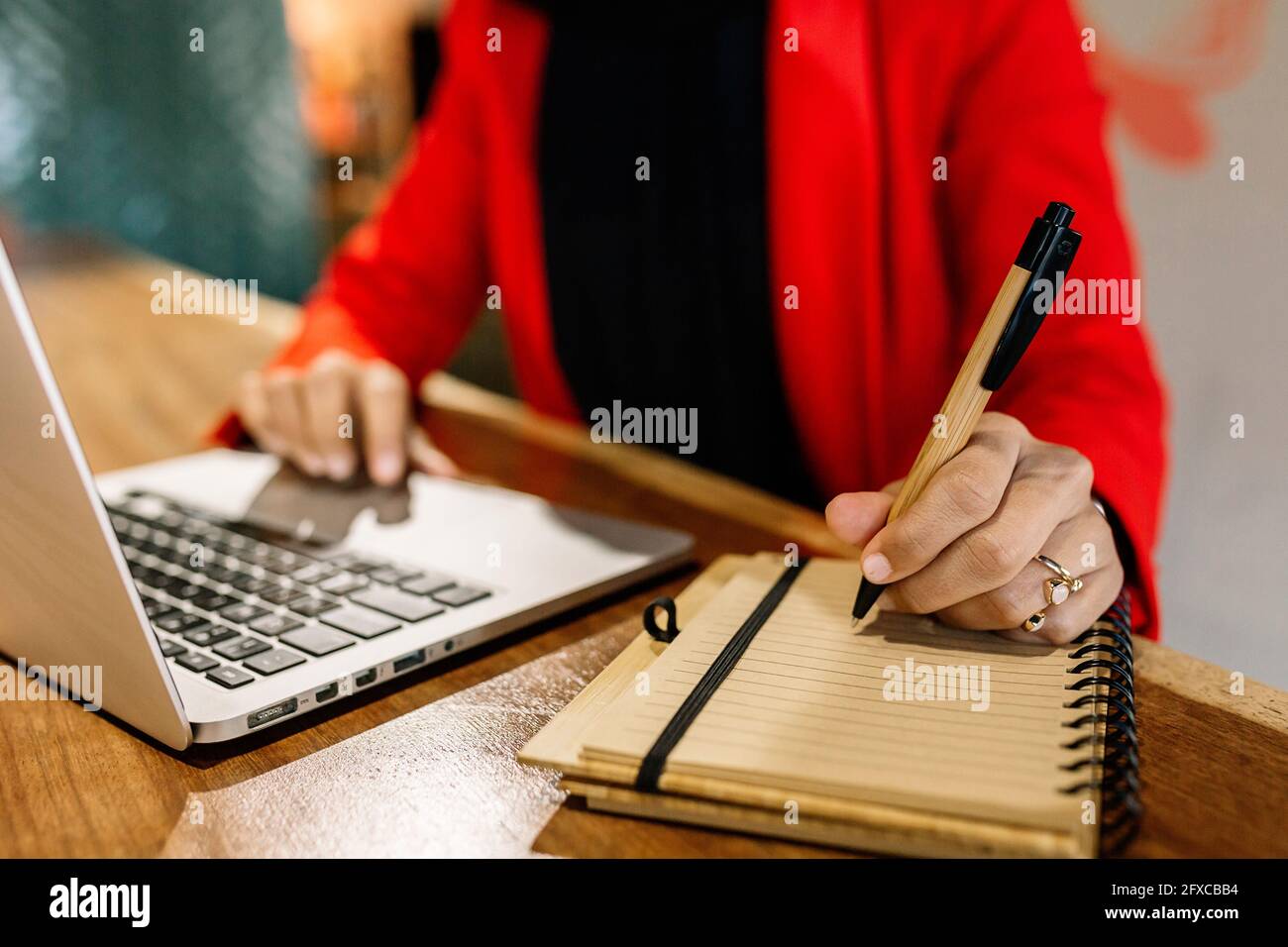 Geschäftsfrau, die im Café ein Tagebuch schreibt, während sie einen Laptop benutzt Stockfoto