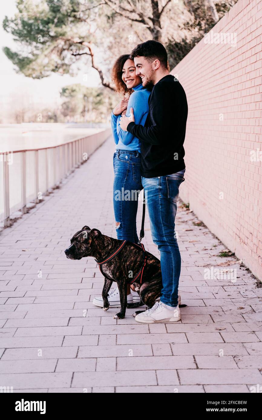 Junges Paar, das zusammen mit Hund auf dem Fußweg steht Stockfoto