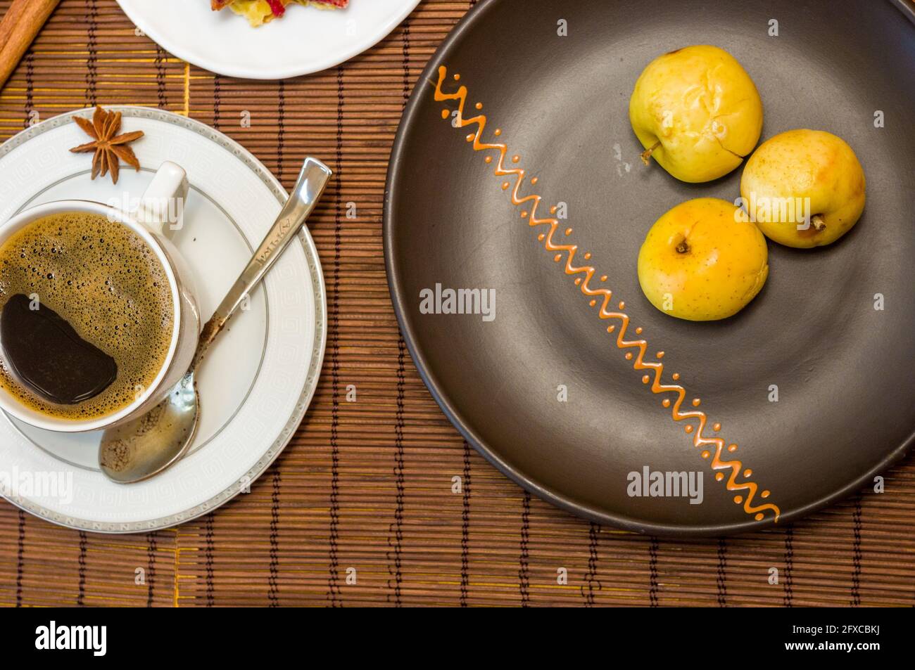 Stillleben - eine Tasse schwarzen Kaffee, hausgemachte Kekse mit Obst, gebackene Äpfel auf einer Bambusmatte Stockfoto