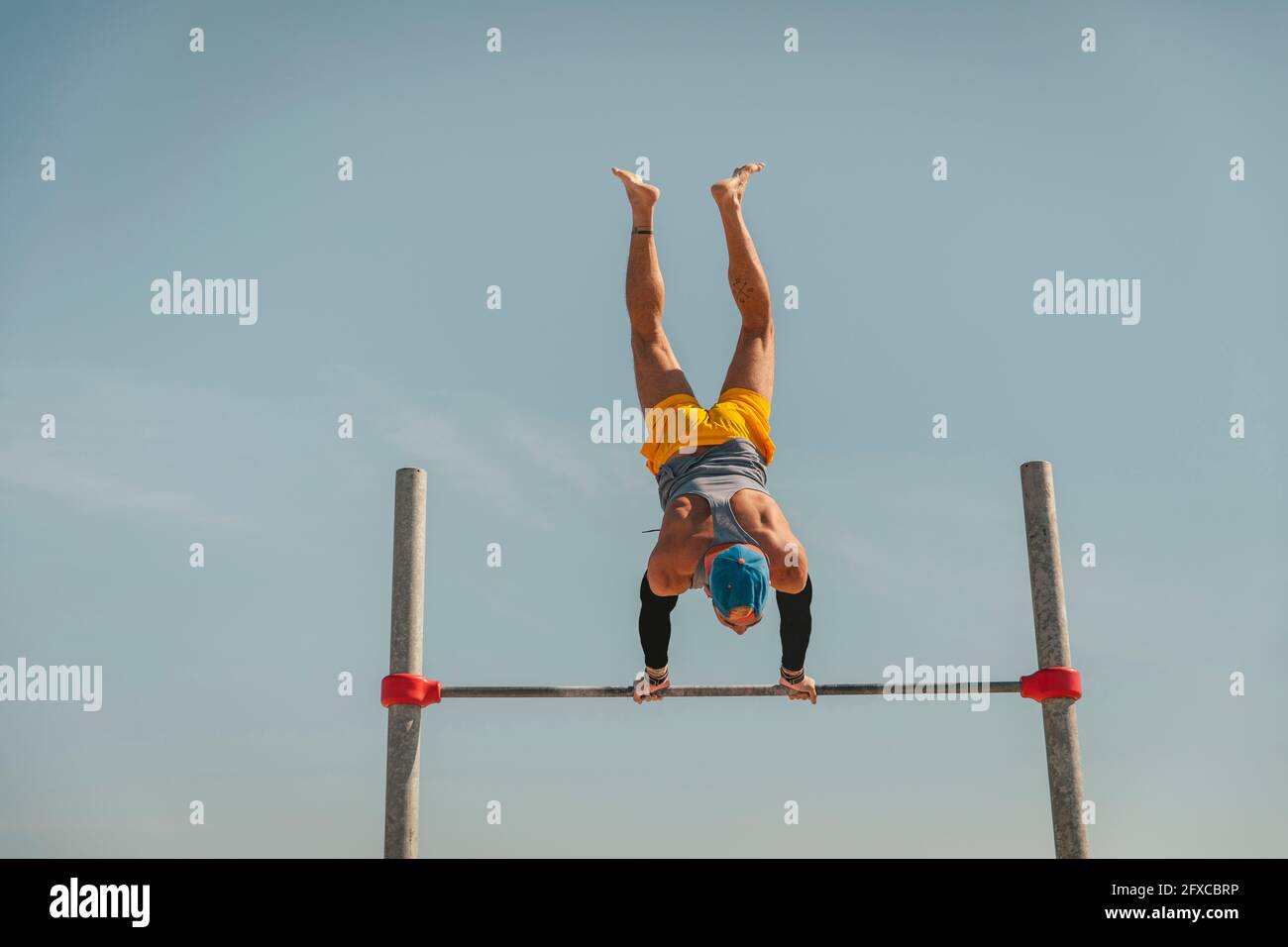 Männlicher Turner, der Handstand auf der hohen Stange macht Stockfoto