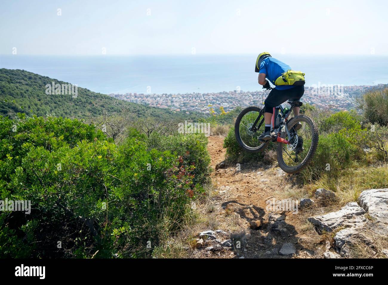 Männlicher Radfahrer in der Luft mit Elektro-Mountainbike an sonnigen Tagen Stockfoto