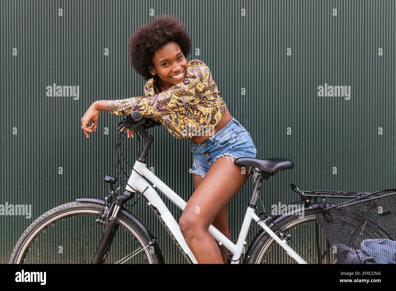 Schöne Frau, die an einer Wand auf dem Fahrrad gelehnt ist Stockfoto