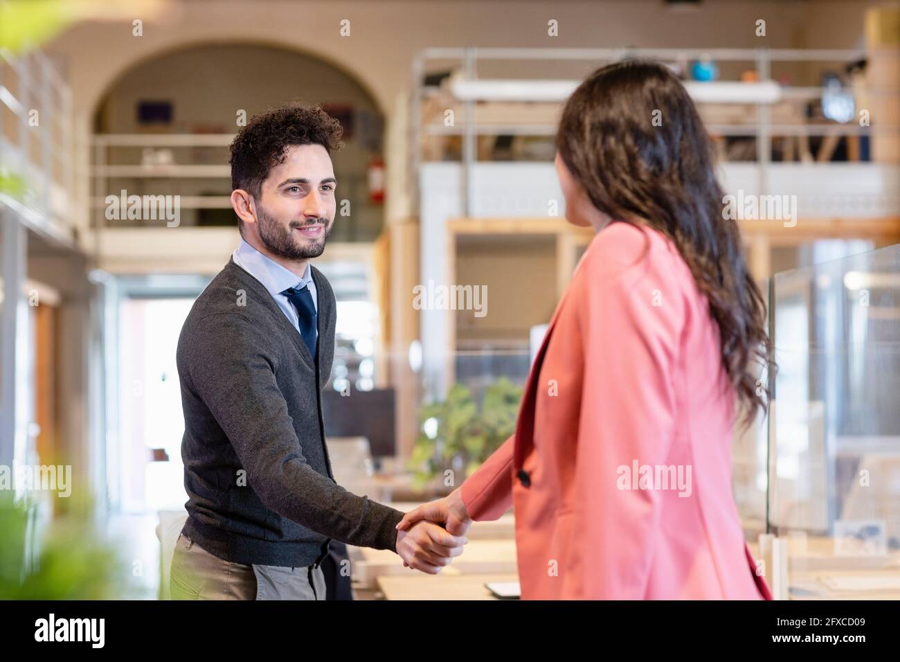 Junge Geschäftsfrau schüttelt sich im Coworking-Büro die Hände mit der Unternehmerin Stockfoto