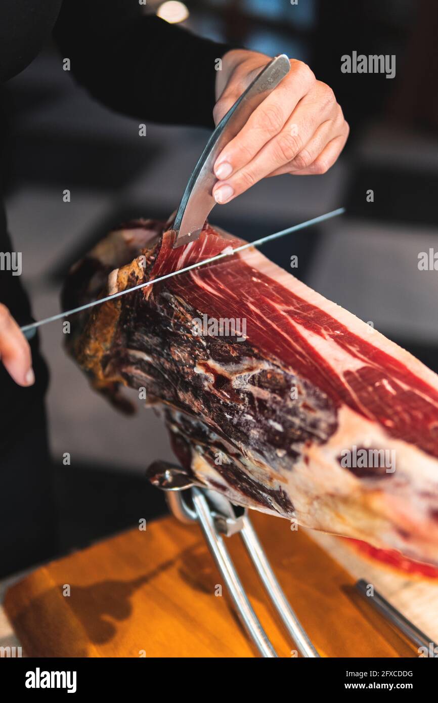 Küchenchef schneidet Schinken mit Küchenmesser im Restaurant Stockfoto