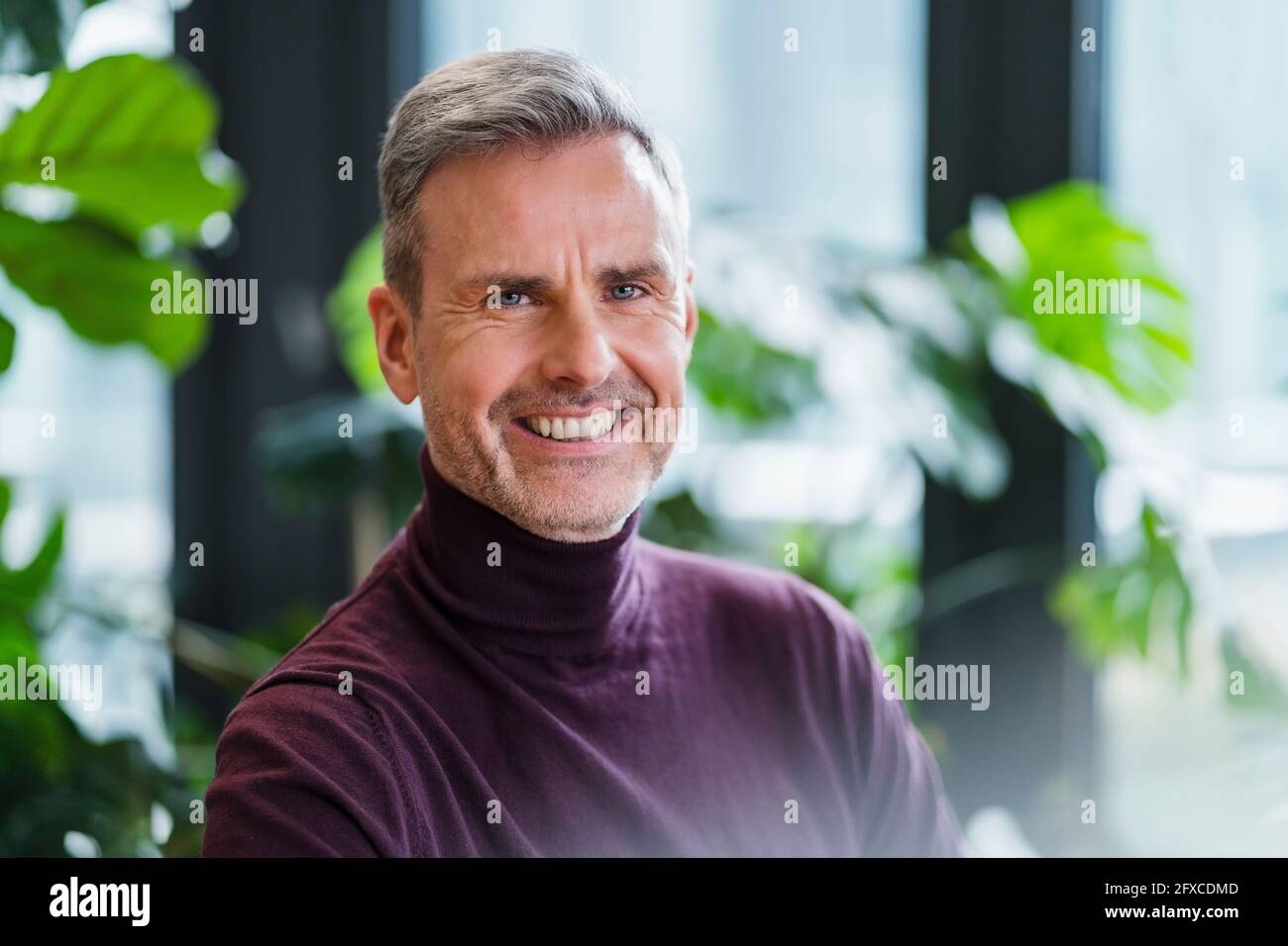 Lächelnder männlicher Profi mit blauen Augen am Arbeitsplatz Stockfoto Lächelnder männlicher Profi mit blauen Augen am Arbeitsplatz Stockfoto