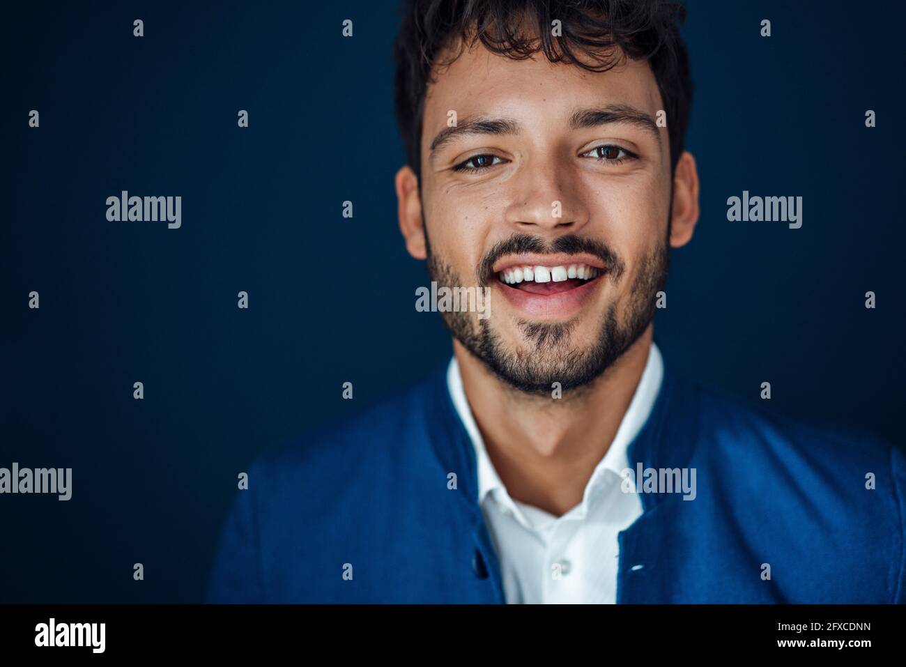 Lächelnder junger Mann vor blauem Hintergrund Stockfoto