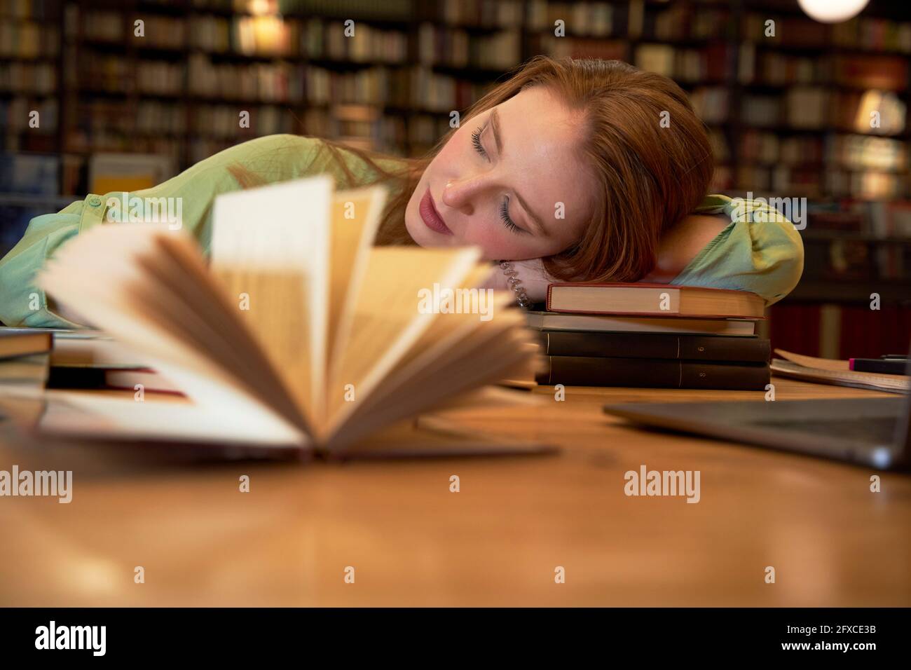 Müde Frau, die in der Bibliothek schläft Stockfoto