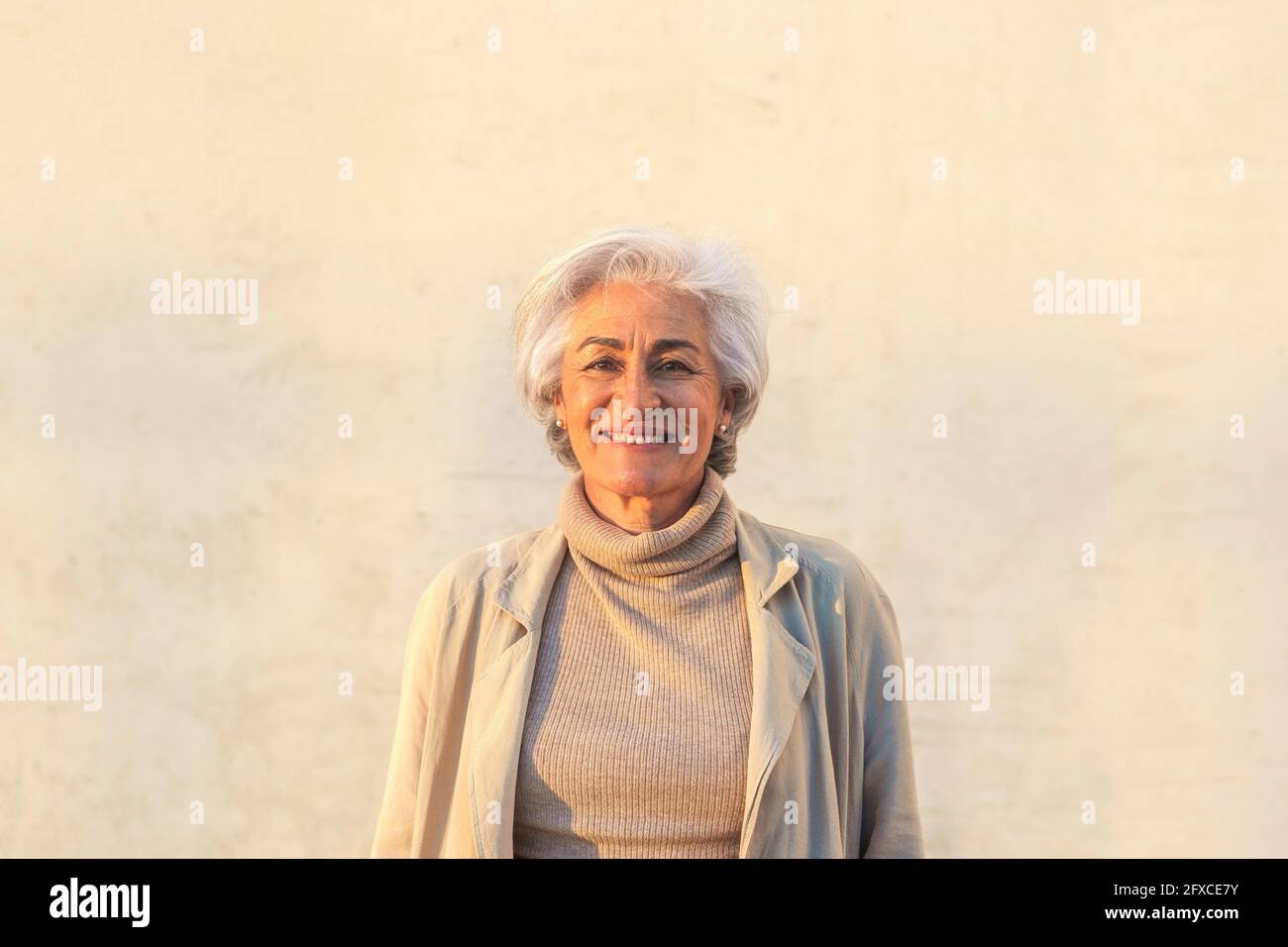 Reife Frau lächelt vor der Wand Stockfoto