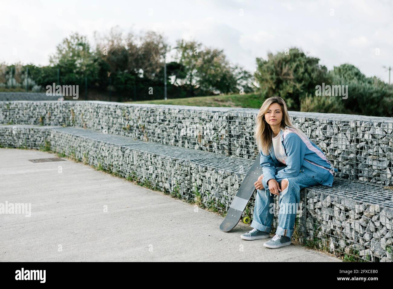 Frau, die auf einer Steinbank im Skateboard-Park sitzt Stockfoto
