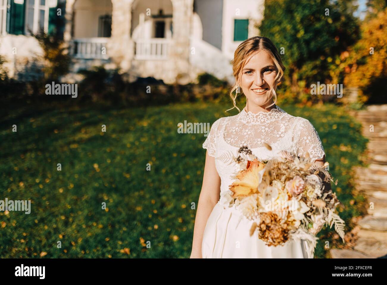 Lächelnde Braut mit Blumenstrauß während der Hochzeitszeremonie Stockfoto