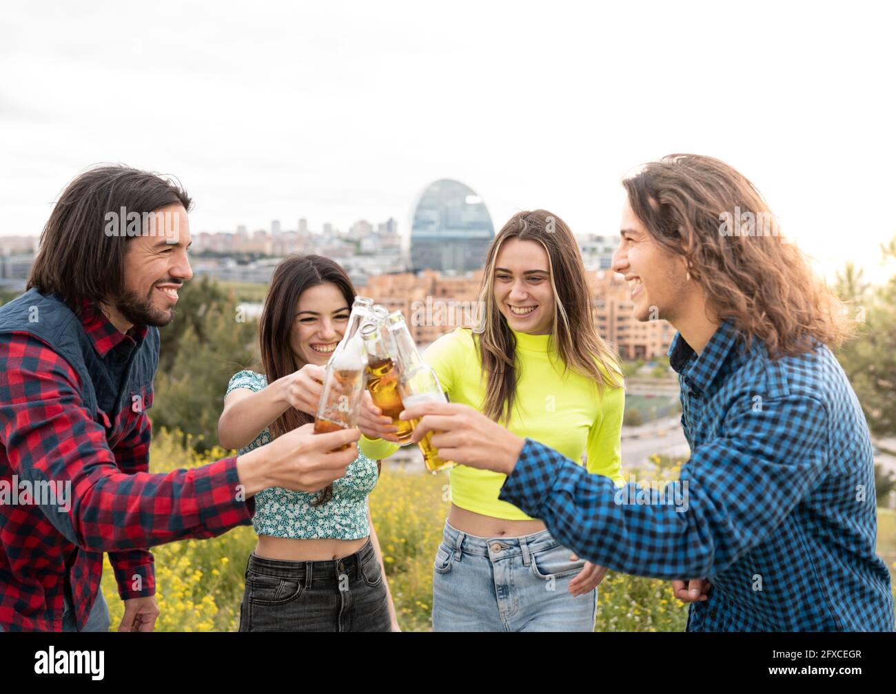 Langhaarige Männer mit Frauen, die Bierflaschen rösten Stockfoto