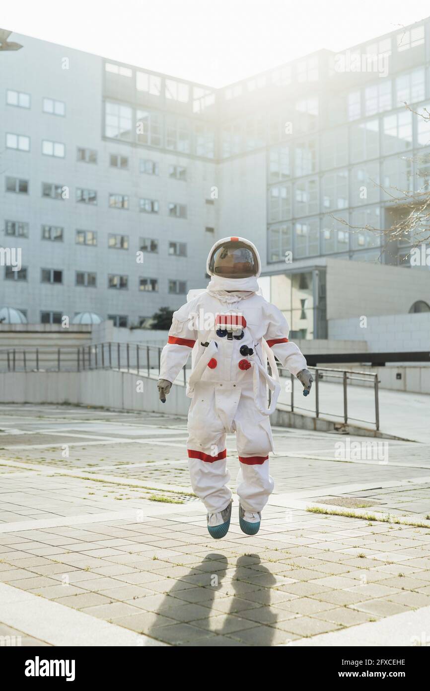 Weibliche Astronautin in der Luft in der Nähe des Gebäudes an sonnigen Tagen Stockfoto
