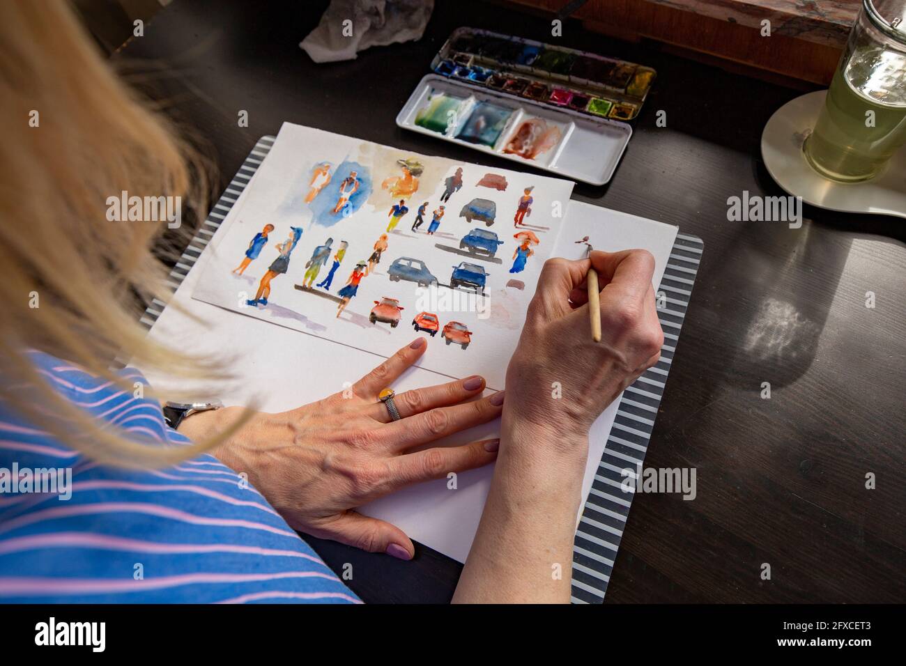 Reife Frau malt mit Aquarell auf Papier am Tisch Stockfoto