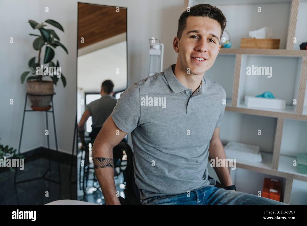 Junger Mann, der in der medizinischen Praxis auf dem Rollstuhl sitzt Stockfoto