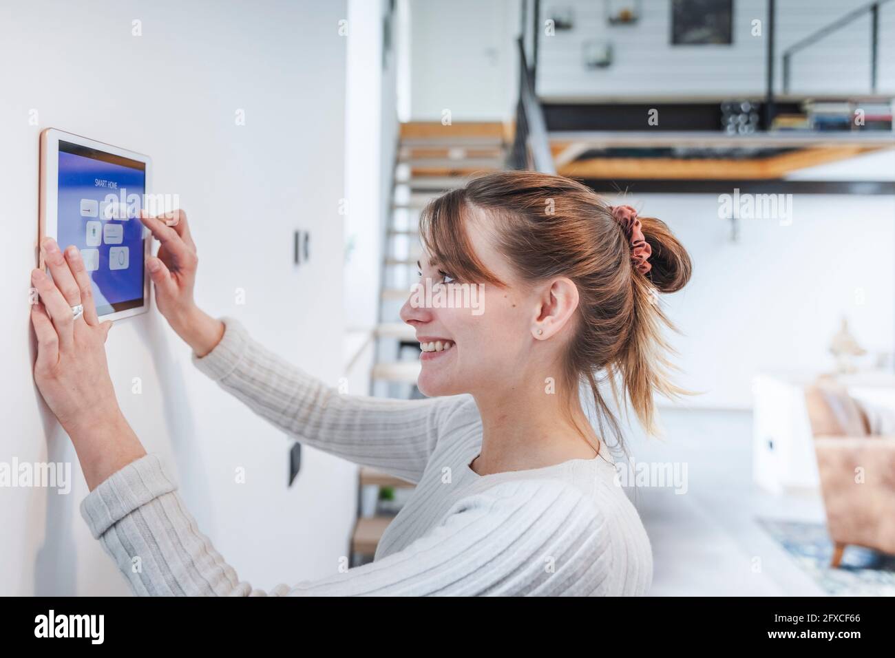Glückliche junge Frau, die zu Hause auf das Bedienfeld schaut Stockfoto