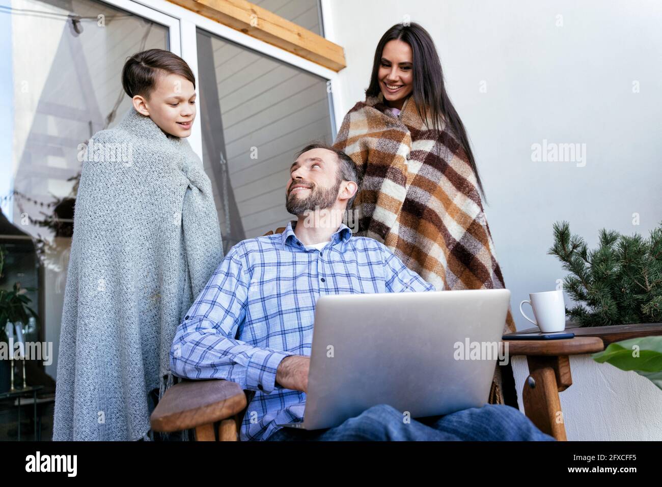 Vater sieht den Sohn, der mit der Mutter auf dem Balkon steht Stockfoto