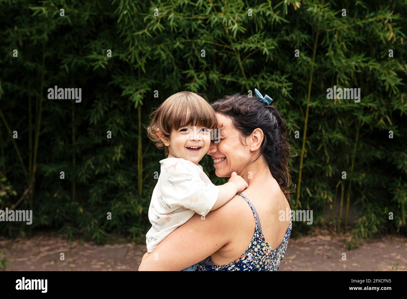 Liebevolle Mutter lächelt beim Tragen mit blondem Sohn Stockfoto