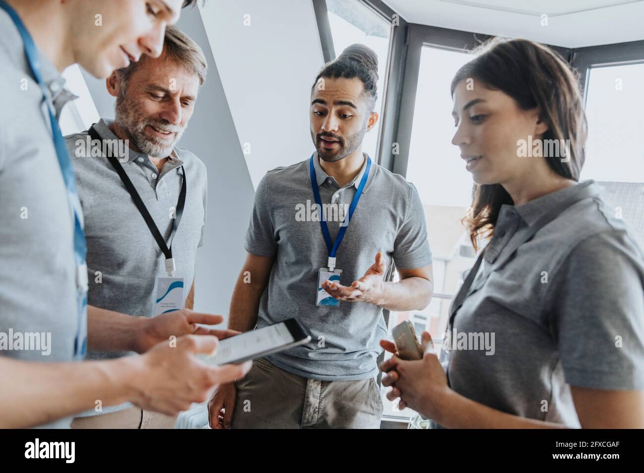 Männlicher Fachmann, der während der Konferenz über ein digitales Tablet mit Kollegen diskutiert Stockfoto