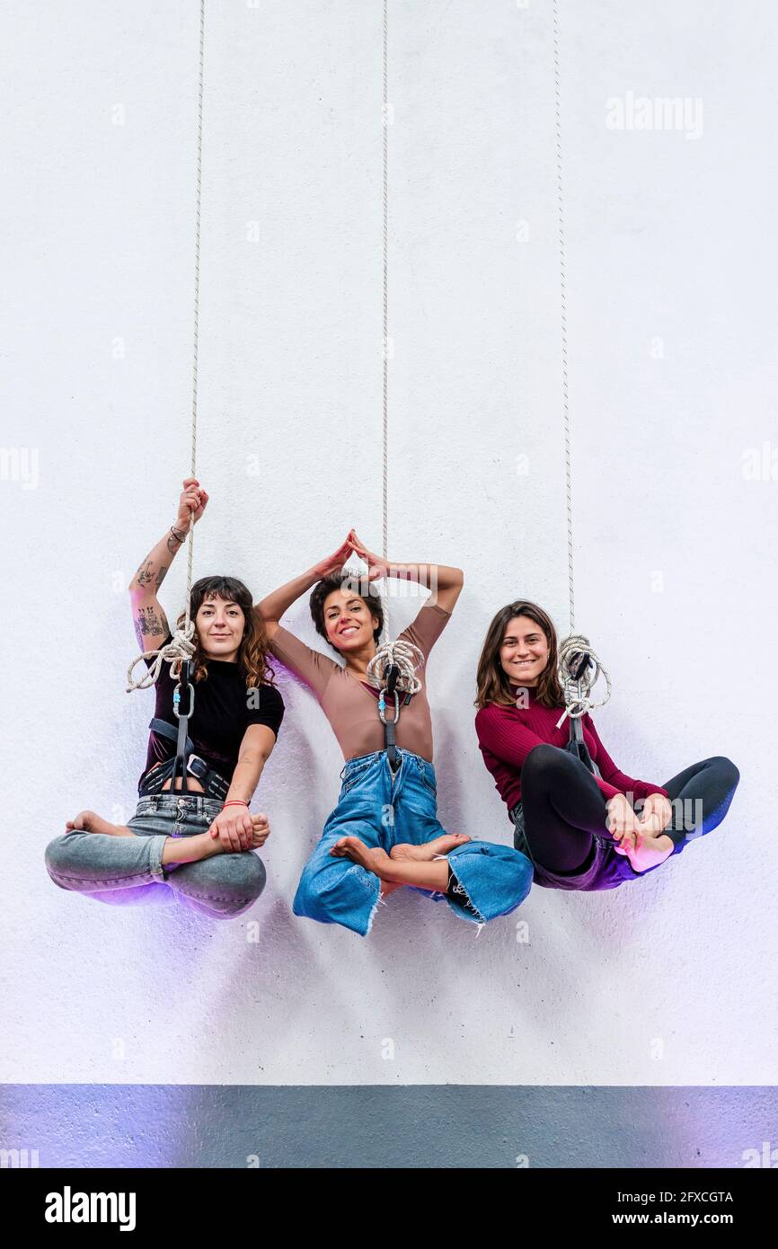 Leidenschaftliche Tänzerinnen mit gekreuzten Beinen, die im Studio am Seil hängen Stockfoto