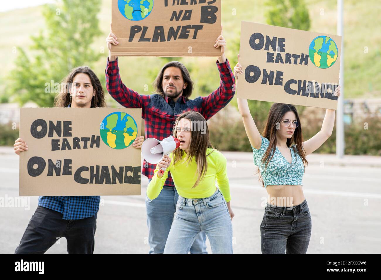Junge Frauen mit Männern protestieren auf dem Weg zum Klimawandel Stockfoto