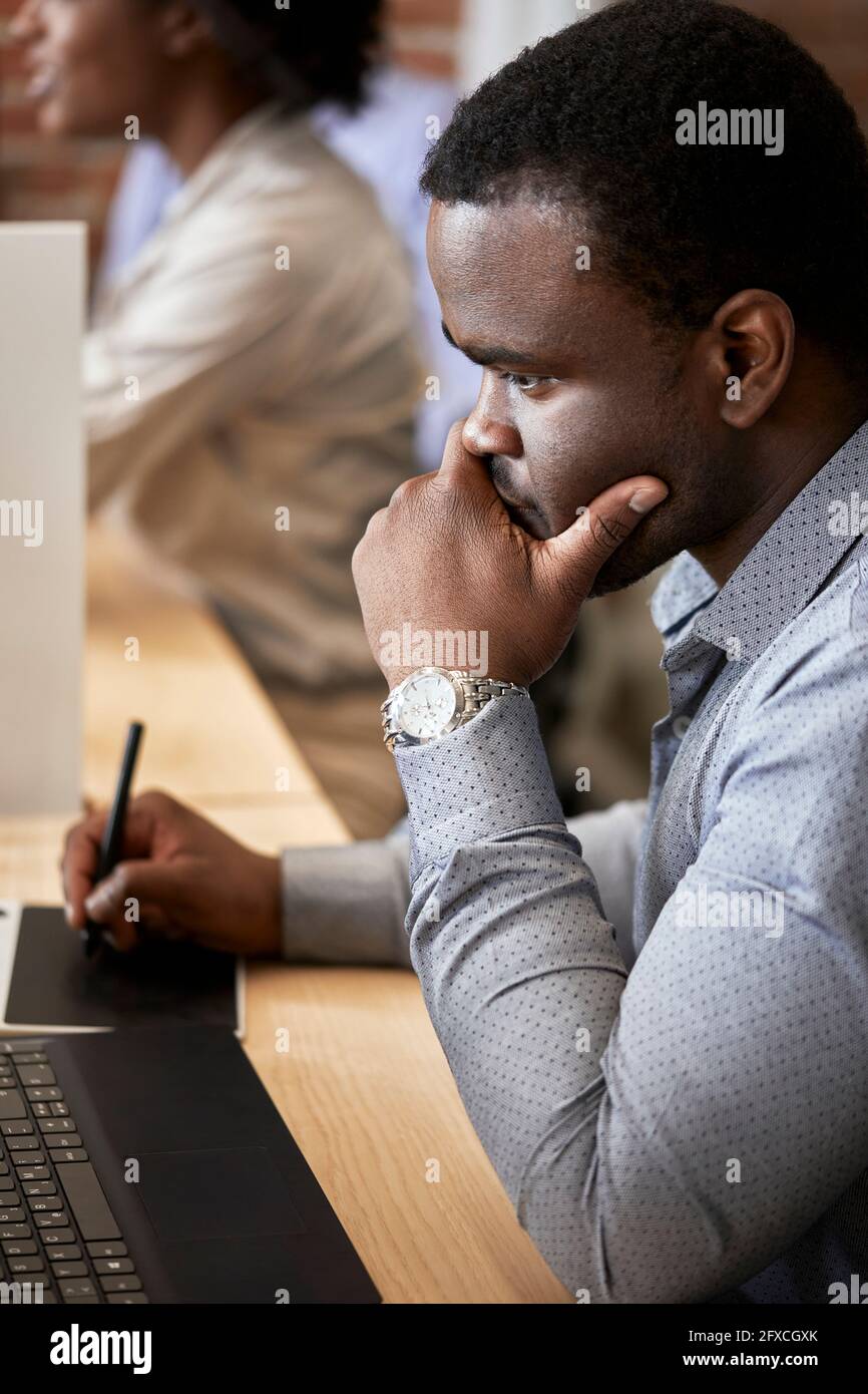 Durchdachter männlicher Designprofi mit grafischem Tablet im Coworking-Büro Stockfoto Durchdachter männlicher Designprofi mit grafischem Tablet im Coworking-Büro Stockfoto
