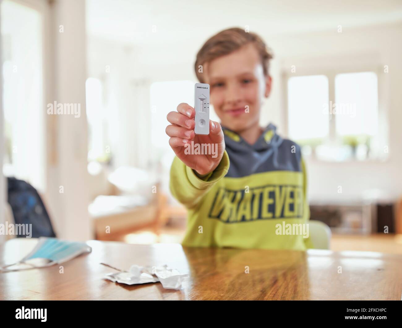 Lächelnder Junge, der zu Hause eine schnelle diagnostische Testprobe zeigt Stockfoto