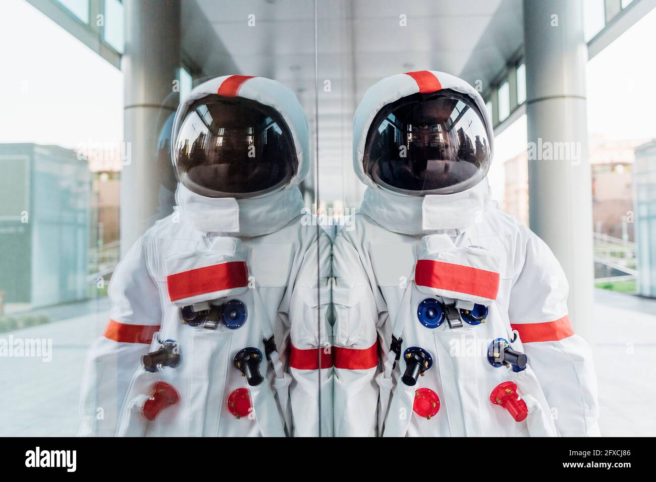 Männlicher Astronaut, der sich an einer Glaswand lehnt Stockfoto