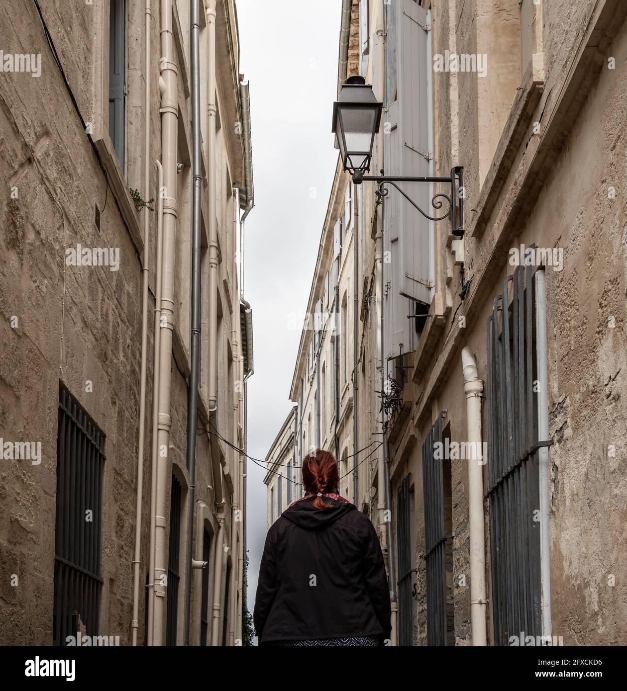 Frau mit roten Haaren in einer traditionellen engen Straße in einer alten europäischen Stadt - Montpellier, Südfrankreich Stockfoto