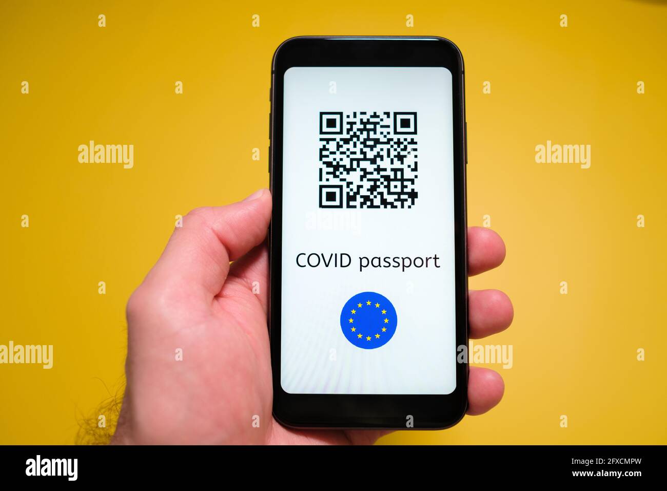 Ein Smartphone mit elektronischem Immun-digitalem Gesundheitspass, Covid-Pass mit QR-Code in mans-Hand auf gelbem Hintergrund. Stockfoto