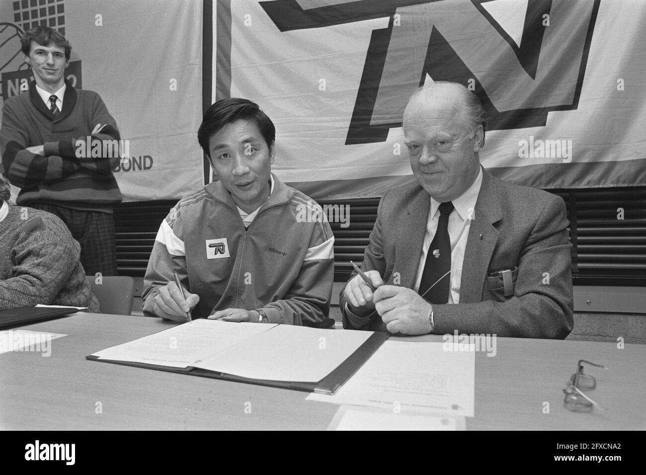 Pang Wugiang (l) unterzeichnet Vertrag mit Ned. Volleyballverband für neue Frauen-Nationalmannschaftscoach; rechts, Verbandspräsidentin Piet de Bruin, 3. Dezember 1986, Verträge, Unterzeichungen, Volleyball, Niederlande, Foto der Presseagentur des 20. Jahrhunderts, Nachrichten zum erinnern, Dokumentarfilm, historische Fotografie 1945-1990, visuelle Geschichten, Menschliche Geschichte des zwanzigsten Jahrhunderts, Momente in der Zeit festzuhalten Stockfoto