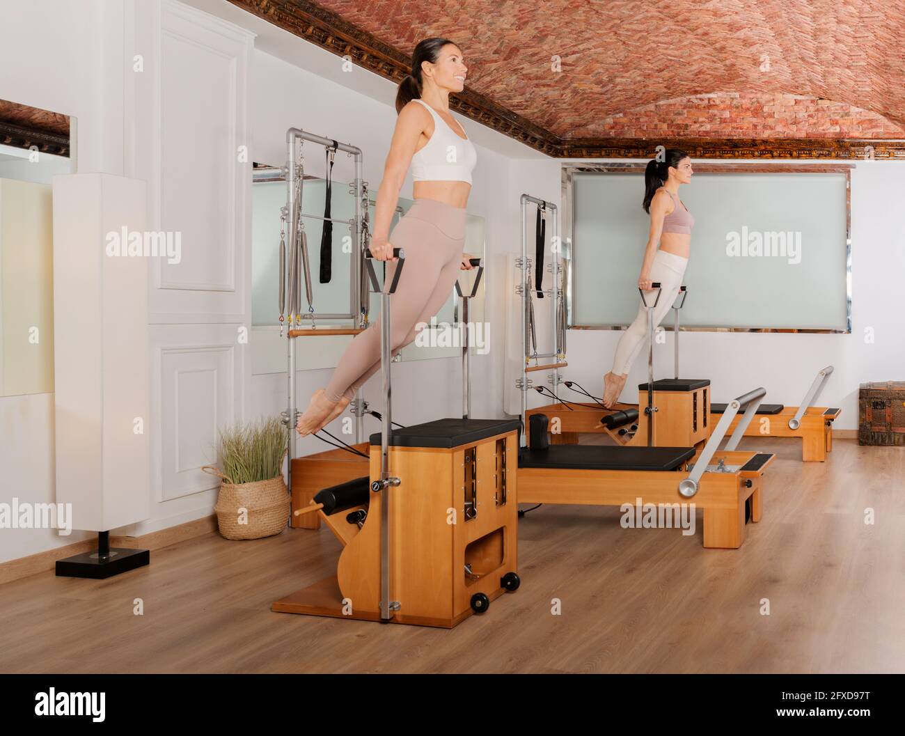 Zwei Mädchen trainieren die Arme auf dem Kombistuhl Pilates Stockfoto