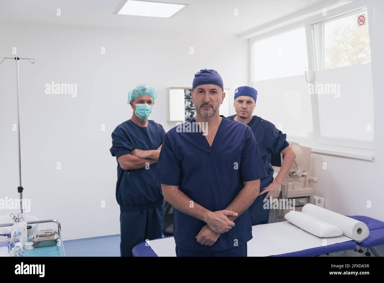 Multiethnischer orthopädischer Arzt vor seinem medizinischen Team sucht An der Kamera trägt Gesichtsmaske Stockfoto
