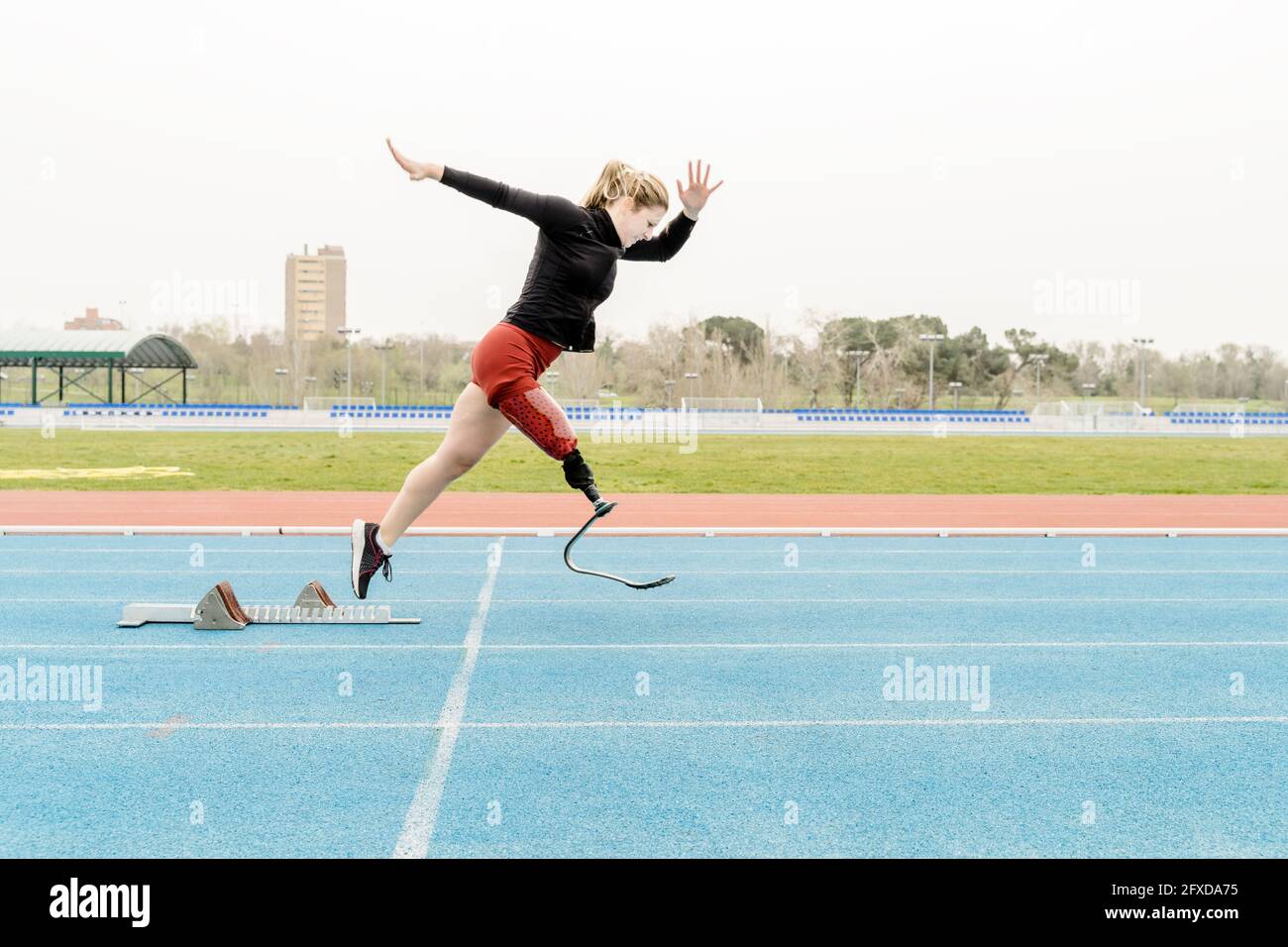 Sportlerin mit Beinprothese in der Nähe der Startblöcke Stockfoto