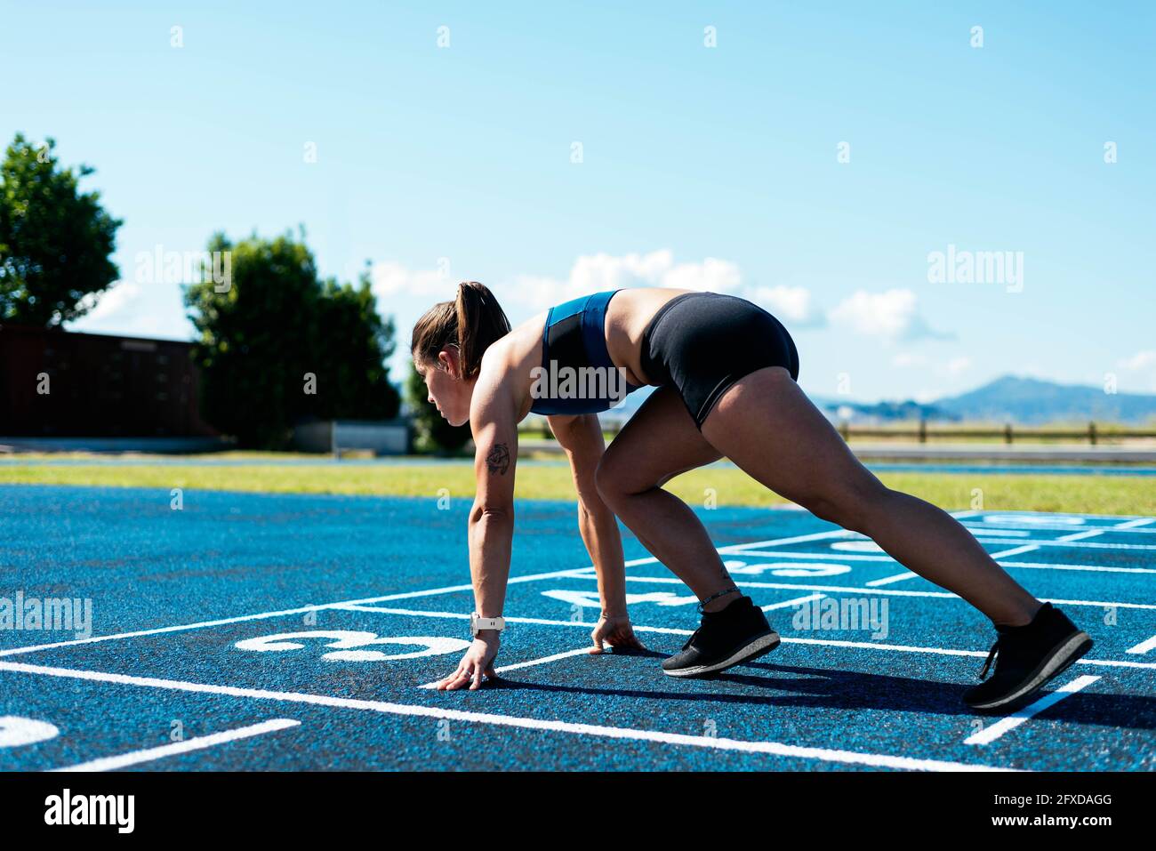 Athletin auf dem Lauffeld in Startposition Stockfoto