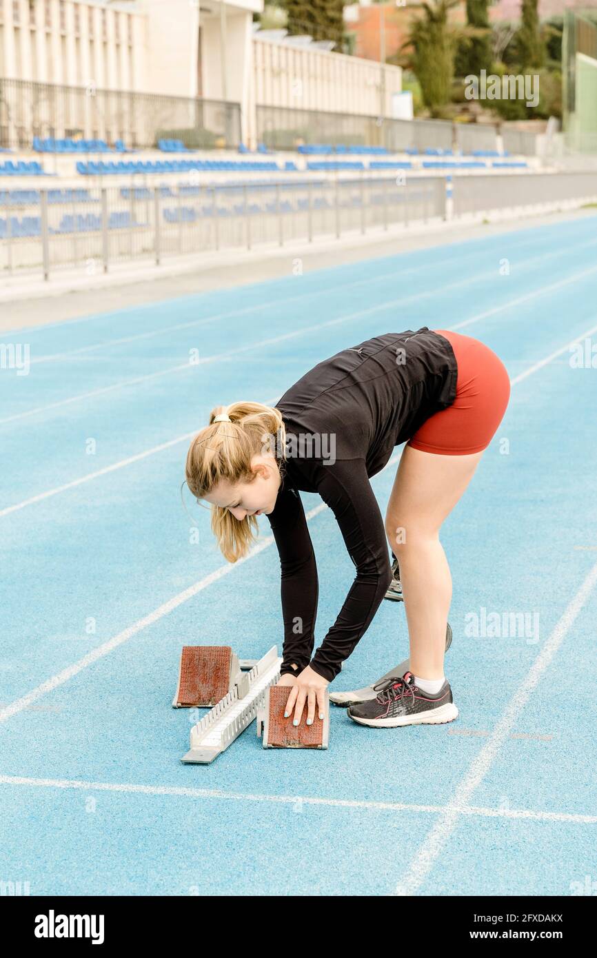 Weibliche Athletin mit Beinprothese, die Startblöcke vorbereitet Stockfoto